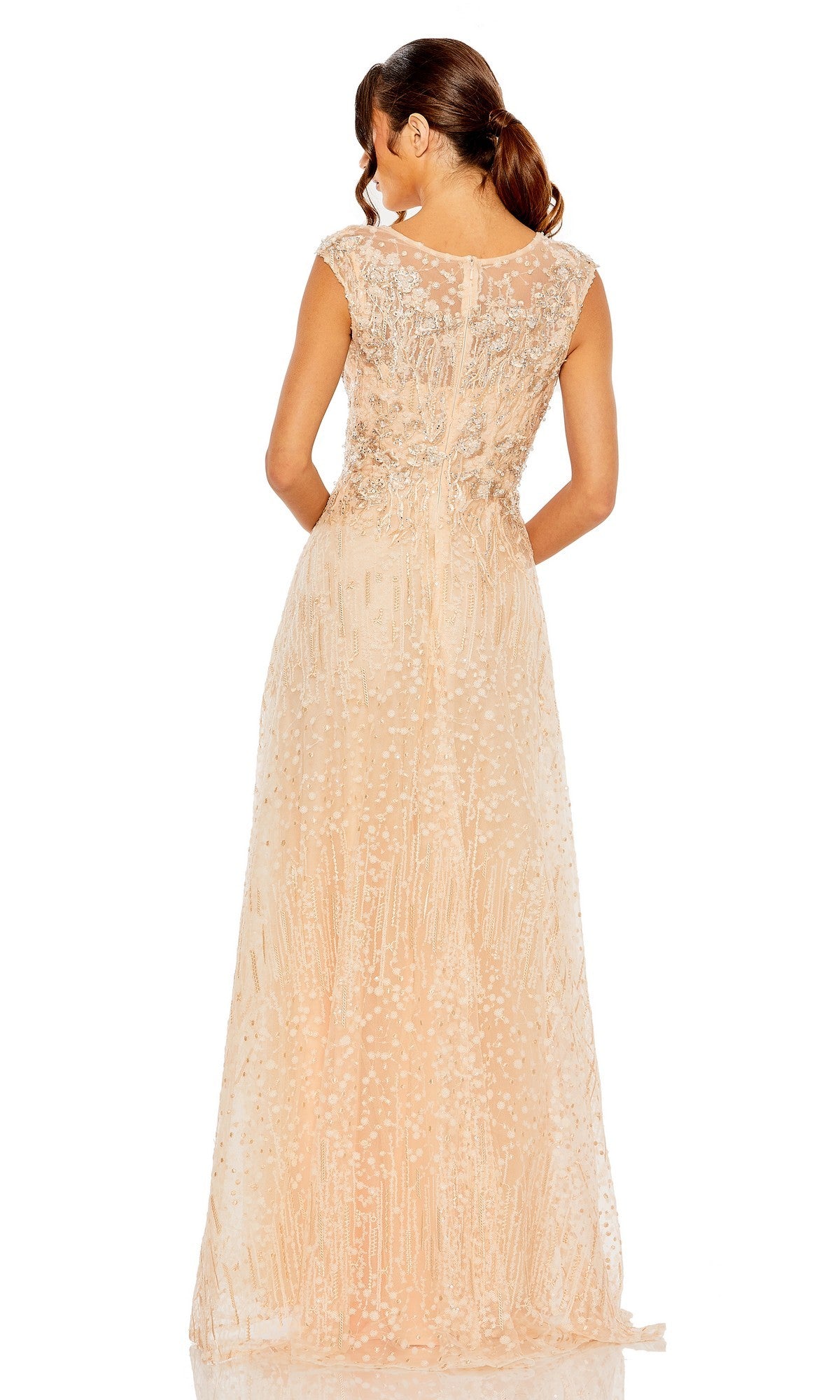 A woman in the Mac Duggal 20501 long formal dress, featuring a sleeveless design, sequin accents, and delicate lace overlay in light peach, stands facing away from the camera against a white background.